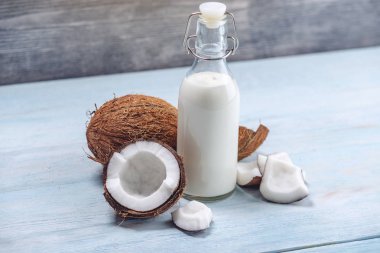 Mavi ahşap arka plan üzerinde beyaz et ile bir şişe hindistan cevizi sütü. Kozmetolojide kullanılan organik ürün