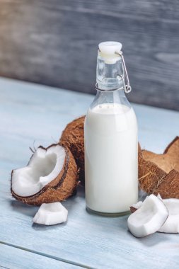 Mavi ahşap arka plan üzerinde beyaz et ile bir şişe hindistan cevizi sütü. Kozmetolojide kullanılan organik ürün