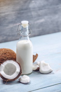 Mavi ahşap arka plan üzerinde beyaz et ile bir şişe hindistan cevizi sütü. Kozmetolojide kullanılan organik ürün