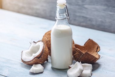 Mavi ahşap arka plan üzerinde beyaz et ile bir şişe hindistan cevizi sütü. Kozmetolojide kullanılan organik sağlıklı ürün