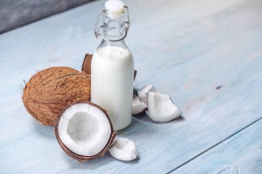 Mavi ahşap arka plan üzerinde beyaz et ile bir şişe hindistan cevizi sütü. Kozmetolojide kullanılan organik sağlıklı ürün