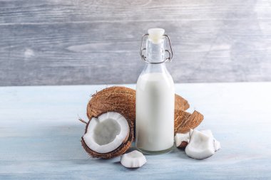 Mavi ahşap arka plan üzerinde beyaz et ile bir şişe hindistan cevizi sütü. Kozmetolojide kullanılan organik sağlıklı ürün