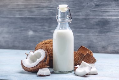 Mavi ahşap arka plan üzerinde beyaz et ile bir şişe hindistan cevizi sütü. Kozmetolojide kullanılan organik sağlıklı ürün