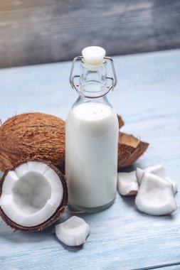 Mavi ahşap arka plan üzerinde beyaz et ile bir şişe hindistan cevizi sütü. Kozmetolojide kullanılan organik sağlıklı ürün