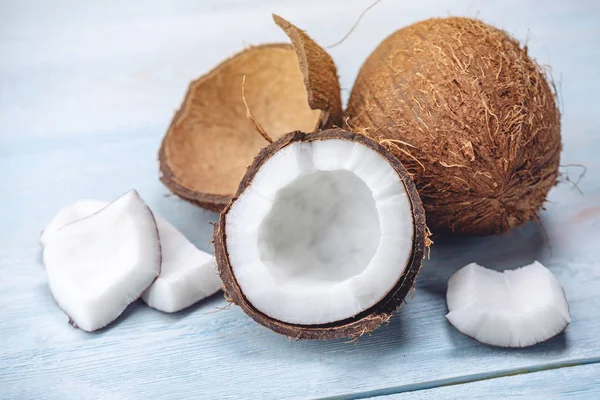 Mavi ahşap arka plan üzerinde beyaz hamuru ile açık hindistan cevizi. Kozmetikte yaygın olarak kullanılan organik sağlıklı vegan ürün