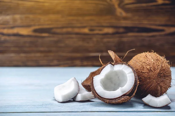 Mavi ahşap arka plan üzerinde beyaz hamuru ile açık hindistan cevizi. Kozmetikte yaygın olarak kullanılan organik sağlıklı vegan ürün