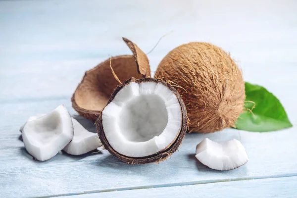 Mavi ahşap arka plan üzerinde beyaz hamuru ile açık hindistan cevizi. Kozmetikte yaygın olarak kullanılan organik sağlıklı vegan ürün