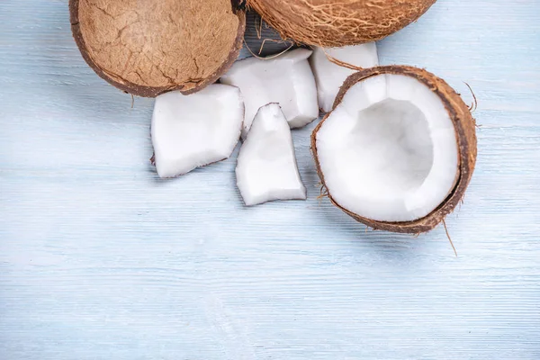 Mavi ahşap arka plan üzerinde beyaz hamuru ile açık hindistan cevizi. Kozmetikte yaygın olarak kullanılan organik diyet vegan ürün