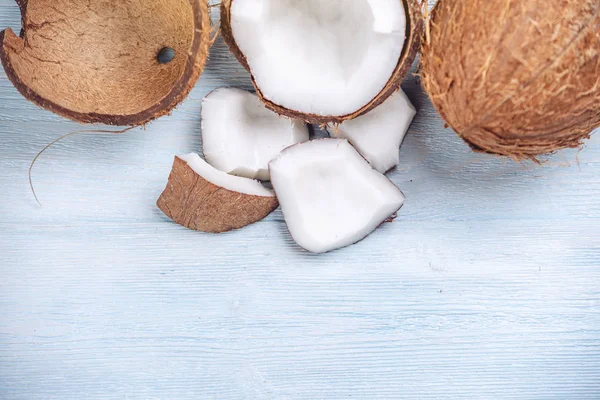 Mavi ahşap arka plan üzerinde beyaz hamuru ile açık hindistan cevizi. Kozmetikte yaygın olarak kullanılan organik diyet vegan ürün
