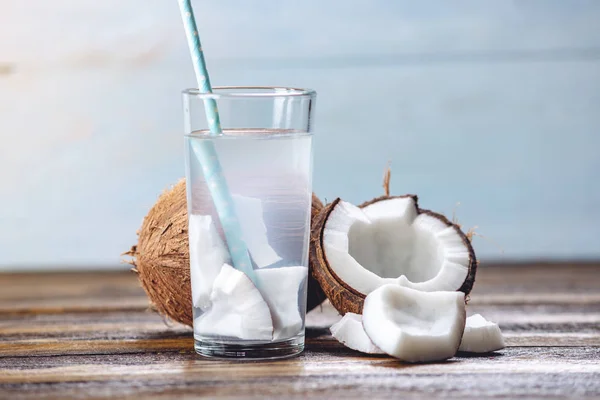Coconut water in the composition with white flesh on wooden background. Organic product widely used in cosmetology