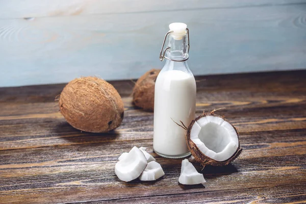 Ahşap bir arka plan üzerinde beyaz et ile bir şişe hindistan cevizi sütü. Kozmetolojide kullanılan organik sağlıklı ürün
