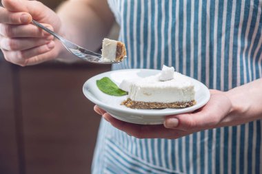 Ahşap bir arka plan üzerinde beyaz hamuru ve nane ile hindistan cevizi çiğ kek Parçası. Vegan tatlısı. Gluten ve şekersiz gıda