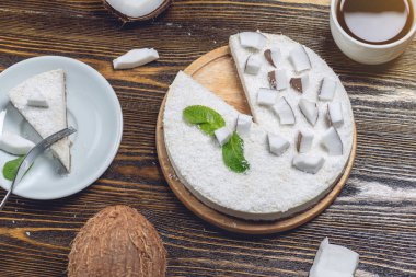 Ham hindistan cevizi kek ahşap bir arka plan üzerinde beyaz hindistan cevizi hamuru ve nane ile dekore edilmiştir. Sağlıklı vegan tatlısı.