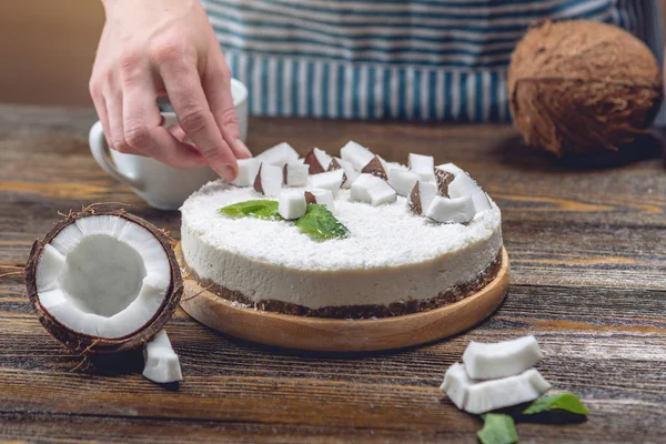 Кондитер украшает кокосовый сырой торт белой мятой и мятой. Здоровый веганский десерт. Без глютена и сахара — стоковое фото