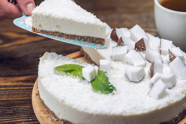 Кондитер держит кусок кокосового сырого торта с белой мякотью. Здоровый веганский десерт. Без глютена и сахара — стоковое фото