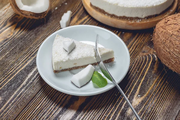 Сырой кокосовый торт украшен белой кокосовой мятой и мятой на деревянном фоне. Здоровый веганский десерт . — стоковое фото