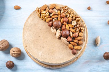 Mavi bir arka plan üzerinde ceviz, badem, fındık ve macadamia tepesi ile Nutty karamel cheesecake. Ev yapımı tatlı.