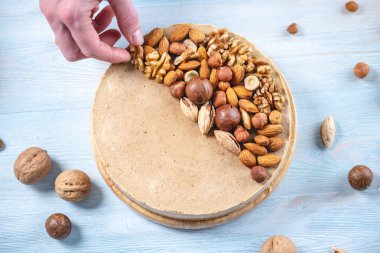 Ceviz, badem, mavi ahşap arka plan üzerinde fındık ile süslenmiş çiğ fındık kek. Glutensiz ve şekersiz gıda