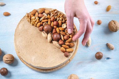 Mavi bir arka plan üzerinde ceviz, badem, fındık ve macadamia tepesi ile Nutty karamel cheesecake. Ev yapımı tatlı.