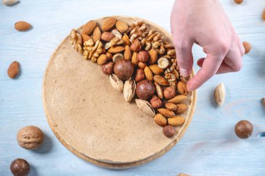 Ceviz, badem, mavi ahşap arka plan üzerinde fındık ile süslenmiş çiğ fındık kek. Glutensiz ve şekersiz gıda