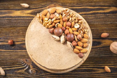 Koyu ahşap bir arka plan üzerinde ceviz, badem, fındık ve macadamia tepesi ile Nutty cheesecake. Ev yapımı tatlı.