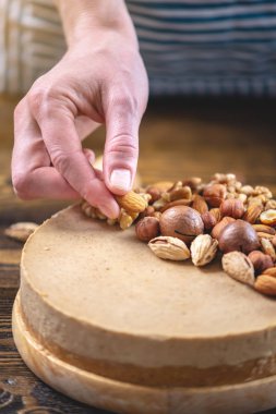 Koyu ahşap arka plan üzerinde ceviz, badem, fındık ile süslenmiş çiğ fındık kek. Sağlıklı taze vegan tatlı.