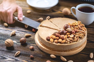 Koyu ahşap arka plan üzerinde ceviz, badem, fındık ile süslenmiş çiğ fındık kek. Sağlıklı taze vegan tatlı.