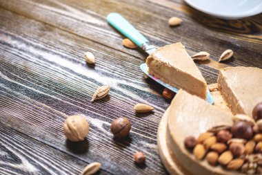 Koyu ahşap arka plan üzerinde ceviz, badem, fındık ile süslenmiş çiğ fındık kek. Sağlıklı taze vegan tatlı.