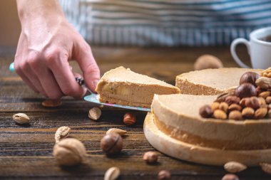 Koyu ahşap arka plan üzerinde ceviz, badem, fındık ve macadamia tepesi ile Nutty karamel cheesecake kek.