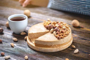 Koyu ahşap arka plan üzerinde nutty cheesecake. Mavi önlüklü şekerlemeci bir parça fındıklı kek tutarken