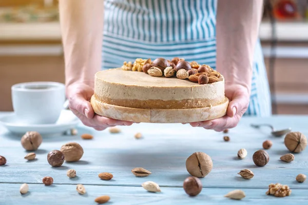 Cheesecake alle noci con guarnizione di noce, mandorla, nocciola. Dolcificante in un grembiule blu decorato dessert fatto in casa . — Foto Stock