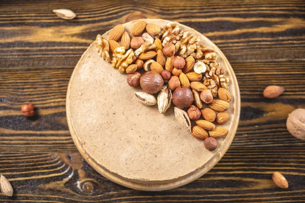 Koyu ahşap bir arka plan üzerinde ceviz, badem, fındık ve macadamia tepesi ile Nutty cheesecake. Ev yapımı tatlı.