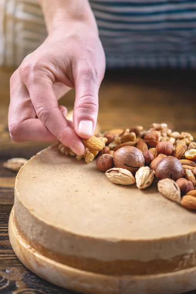 Koyu ahşap arka plan üzerinde ceviz, badem, fındık ile süslenmiş çiğ fındık kek. Sağlıklı taze vegan tatlı.
