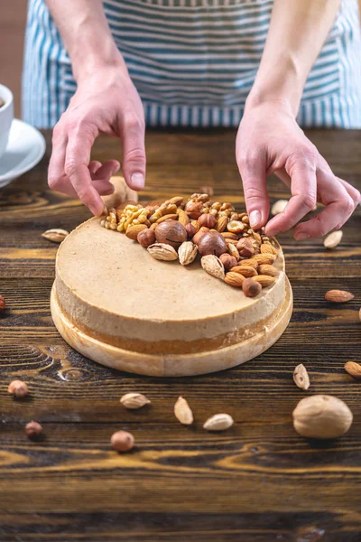 Koyu ahşap arka plan üzerinde ceviz, badem, fındık ile süslenmiş çiğ fındık kek. Sağlıklı taze vegan tatlı.
