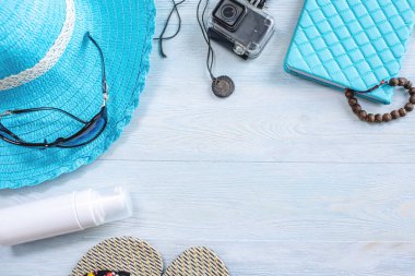 Seyahat tatil malzemeleri: şapka, güneş gözlüğü, parmak arası terlik, mavi arka plan kamera pasaport. Denize bir geziye çıkmak