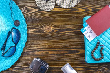 Seyahat tatil malzemeleri: şapka, güneş gözlüğü, parmak arası terlik, pasaport ve eski ahşap arka plan üzerinde uçak biletleri. Üstte görüntü