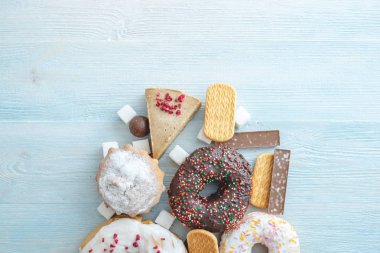 Mavi ahşap arka plan üzerinde Zararlı tatlı gıdalar. Masanın üstünde çörekler ve kekler var. Sağlıksız diyet ve kilolu