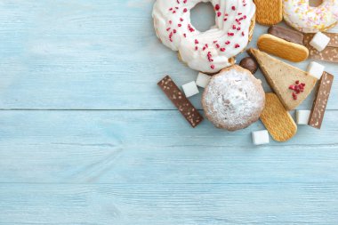 Mavi ahşap arka plan üzerinde Zararlı tatlı gıdalar. Masanın üstünde çörekler ve kekler var. Sağlıksız diyet ve kilolu