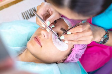 Güzellik salonunda kadın usta müşteri kirpik uzantısı üzerinde çalışır. Güzellik hizmetleri alanında meslek kavramı