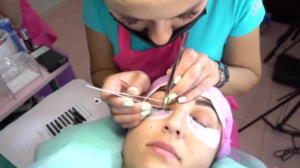 Női mester a szépségszalonban munka szempilla kiterjesztése az ügyfél. Szakma a szépségápolási szolgáltatások területén — Stock videók
