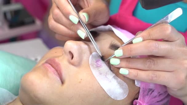 Die Meisterin im Schönheitssalon arbeitet an der Wimpernverlängerung für den Kunden. Beruf im Bereich der Schönheitsdienstleistungen — Stockvideo