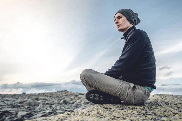 Hombre excursionista sentado en una pose de yoga en la cima de la montaña en el verano. Meditación después de una larga escalada en una montaña — Foto de Stock