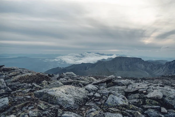 Beautiful view of the mountains from the peak. Landscape with clouds and stones at sunset. Concept climbing and Hiking
