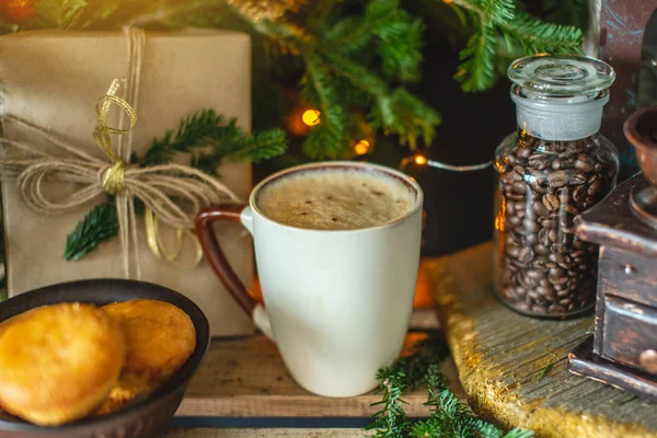 Mug of cappuccino coffee on a wooden background with green branches of a Christmas tree. Warm and cozy from a hot drink. — Stock Photo, Image