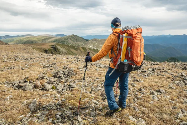 Homem Caminhante com postes de trekking à procura de um vale de montanha com colinas em tempo ensolarado. Viajar e alcançar o objetivo — Fotografia de Stock