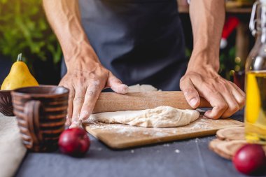 Siyah önlüklü adam şef Noel pişirme için elleriyle hamur yoğuruyor. Şenlikli yeni yıl masası için neşeli pişirme