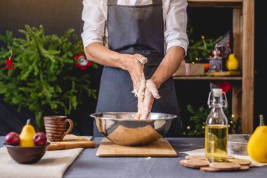 Siyah önlük adam şef Noel pişirme için elleri ile hamur yoğurma. Şenlikli yeni yıl masası için neşeli pişirme