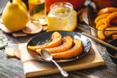Tahta bir masada bal ve tarçın ile pişmiş portakal kabak dilimleri. Tatlı olarak sonbahar yemeği