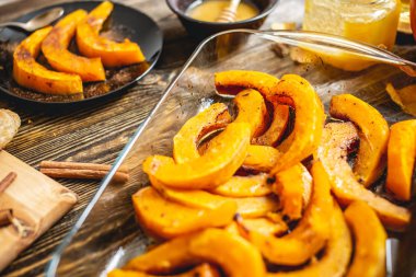 Tahta bir masada bal ve tarçın ile pişmiş portakal kabak dilimleri. Tatlı olarak sonbahar yemeği