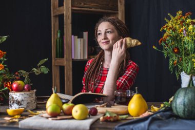 Sonbahar havasının tadını çıkaran sıcak ve sıcak bir atmosferde romantik bir kitap okuyan kadın. Kitap yığını ile Rustik tablo